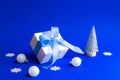 Christmas background. White gift box with blue ribbon, winter tree, Snowflakes and Silver balls in xmas composition on blue Royalty Free Stock Photo