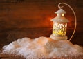 Christmas background with white lantern and snow over wooden background