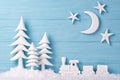 Christmas background with white Christmas trees, toy train, snow, moon and stars, blue wooden background