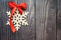 Christmas background with wooden snowflake and red bow on the old wooden board