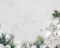 Christmas background with xmas decorations. Silver christmas gift, fir tree branch and baubles ornaments on gray stone table. Royalty Free Stock Photo