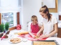 Christmas bakery.Two sisters making gingerbread, cutting cookies of gingerbread dough. Royalty Free Stock Photo