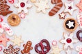 Christmas baking frame with a variety of cookies and sweets on a white marble background