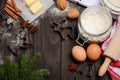 Christmas baking ingredients - cookies cutters, spices, butter, eggs and flour on dark wooden background