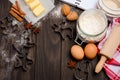 Christmas baking ingredients - cookies cutters, spices, butter, eggs and flour on dark wooden background