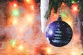 Christmas ball on the background of blurred glass with frost and colored lights with the falling snowflakes Royalty Free Stock Photo