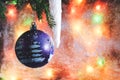 Christmas ball on the background of blurred glass with frost and colored lights with the falling snowflakes Royalty Free Stock Photo