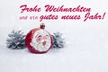 Christmas ball with drawing of Santa Claus and pines with text in German `Frohe Weihnachten und ein gutes neues Jahr`