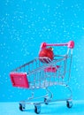 Christmas ball with glitter in the shopping cart against the blue background Royalty Free Stock Photo