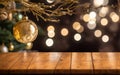 Christmas ball hanging on gold branch above wooden table top. Xmas bokeh lights on background. Royalty Free Stock Photo