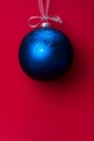 Christmas ball hanging on a ribbon over red background. Copy space. Royalty Free Stock Photo