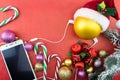 Christmas ball with Santa's hat and smartphone with earphones, on red