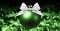 Christmas ball, silver satin ribbon bow on blurred green bright Royalty Free Stock Photo