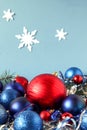 Christmas balls-red and blue-with festive tinsel on a blue background with snowflakes, side view, vertical frame Royalty Free Stock Photo