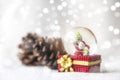 Christmas balls, Santa Claus in a Snow globe, and Pine cones on a white Cloth, set Against a Red Background and exquisite bokeh. Royalty Free Stock Photo