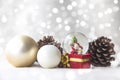 Christmas balls, Santa Claus in a Snow globe, and Pine cones on a white Cloth, set Against a Red Background and exquisite bokeh. Royalty Free Stock Photo