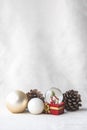 Christmas balls, Santa Claus in a Snow globe, and Pine cones on a white Cloth, set Against a Red Background and exquisite bokeh. Royalty Free Stock Photo