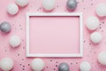 Christmas balls, sequins and picture frame on stylish pink table top view. Fashion background. Flat lay. Party mockup. Royalty Free Stock Photo