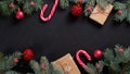 Christmas banner. Black Xmas background with candy cane, decorations, fir tree branches and gift boxes wrapped craft paper. Royalty Free Stock Photo