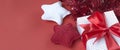 Christmas banner with gift box, tinsel, and knitted stars. Gift concept for needlewoman on a red background Royalty Free Stock Photo