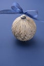 Christmas bauble with blue ribbon, isolated over blue background. Classic blue abstract background. Copy space