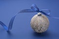Christmas bauble with blue ribbon, isolated over blue background. Classic blue abstract background. Copy space Royalty Free Stock Photo