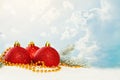 Christmas baubles, gold garland and green fir branch on white snow against blue sky with white clouds. Winter holidays background Royalty Free Stock Photo