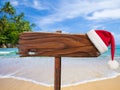 Christmas on beach concept. Wooden signboard with Santa's hat. Royalty Free Stock Photo