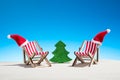 Christmas on the beach: two chairs with Santa hats and toy fir Royalty Free Stock Photo