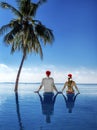 Christmas beach vacation holidays. Santa hat couple relaxing and sitting in the pool. Wide horizontal sky background for text Royalty Free Stock Photo
