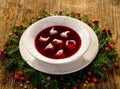 Christmas beetroot soup, red borscht with small dumplings with mushroom filling in a ceramic white plate on a wooden table Royalty Free Stock Photo