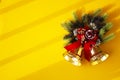 Christmas bells with spruce branches and red bow on yellow background Royalty Free Stock Photo