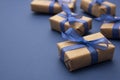 Christmas or birthday presents. Craft paper wrapped gift boxes on blue background, flat lay with copy space