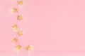 Christmas blank interior with gold shimmer glowing stars garland on soft light pastel pink backdrop, copy space.