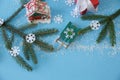 Christmas blue background with Christmas tree branch and red gift boxes with white ribbons, bell, sleigh and snowflakes. Flat lay. Royalty Free Stock Photo
