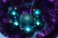 Christmas blue toys lie surrounded by festive purple tinsel, top view