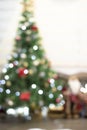 Christmas Blurred Background. Blured white room interior in red tones with New Year tree decorated, present boxes and artificial