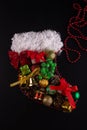 Christmas boot flat lay. Holiday figure made of various new year decorations on black background. Present box, ball, pine tree Royalty Free Stock Photo