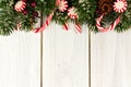 Christmas border of branches and candy canes on white wood