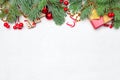 Christmas border composition with green Xmas fir branch, red holly berries and baubles on white texture stucco plaster background