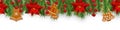 Christmas border decorations with fir branches, poinsettia, holly berries, gingerbread cookies and golden ribbons. Design element Royalty Free Stock Photo