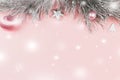 Christmas border with fir branches, christmas balls and silver ornaments on pastel pink background, snow falling