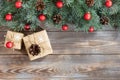 Christmas border with fir branches, red balls, cones and gifts on a wooden background Royalty Free Stock Photo