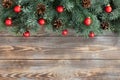 Christmas border with fir branches, red balls and cones on a wooden background Royalty Free Stock Photo