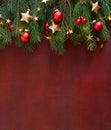 Christmas border with fir branches, red baubles and gold stars on the wooden board painted in dark-red with copy space for text. F Royalty Free Stock Photo