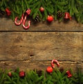 Christmas border with fir tree branches, cones, christmas decorations and candy cane on rustic wooden boards Royalty Free Stock Photo