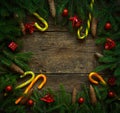 Christmas border with fir tree branches, cones, christmas decorations and candy cane on rustic wooden boards Royalty Free Stock Photo