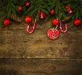 Christmas border with fir tree branches, cones, christmas decorations and candy cane on rustic wooden boards Royalty Free Stock Photo