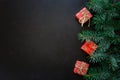 Christmas Border. Fir tree branches with gift boxes on dark wooden background. Royalty Free Stock Photo