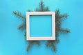 Christmas Border. Fir tree branches and white wooden frame on blue paper background. Top view. Copy space. Royalty Free Stock Photo